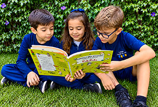 Alunos leem livro no gramado