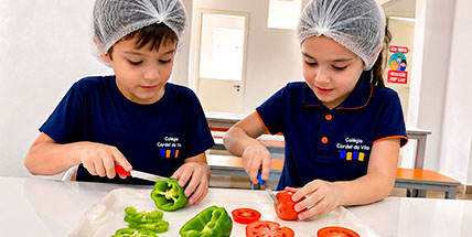 Alunas preparam alimentos em aula de culinária