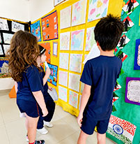 Alunos observam painel de atividades pedagógicas