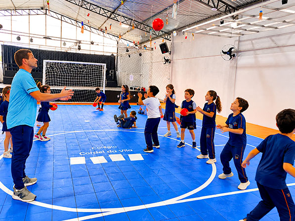 Alunos praticam atividade com bola na quadra